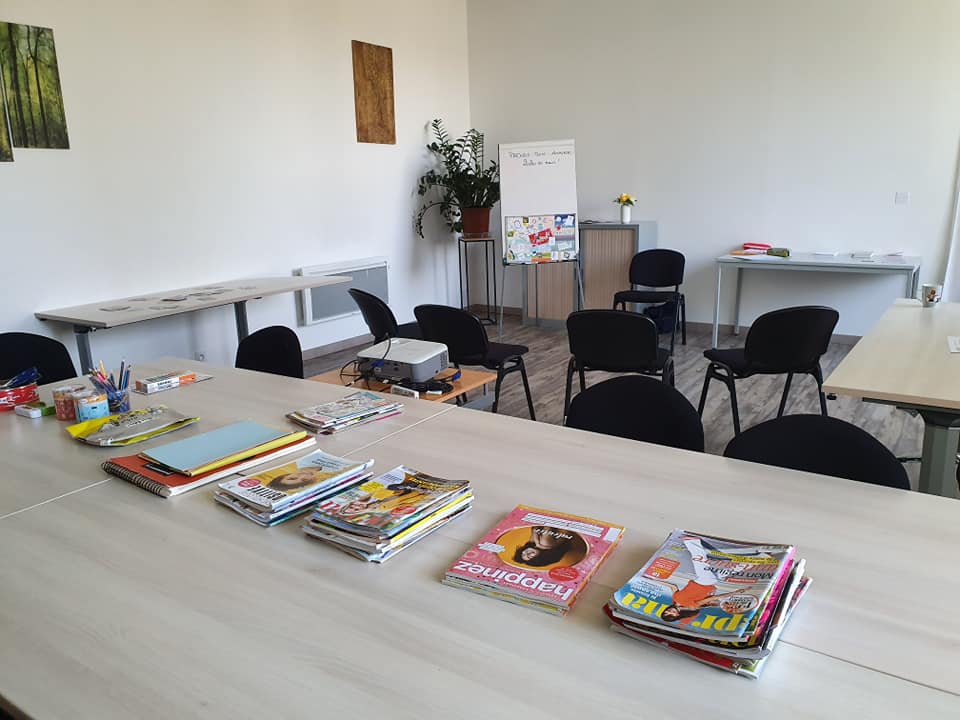Salle préparée pour un atelier collectif avec tables, chaises et matériel créatif